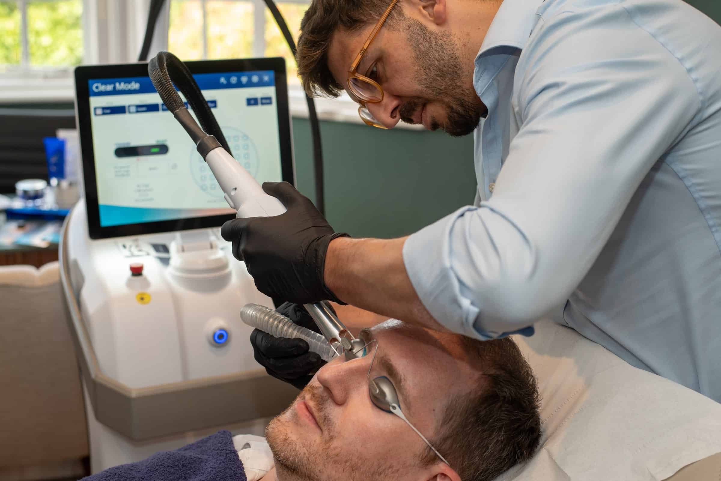 Dr Mattia Parducci treats a patient with UltraClear beside the laser console at Cannelle Skin Clinic in Oxford